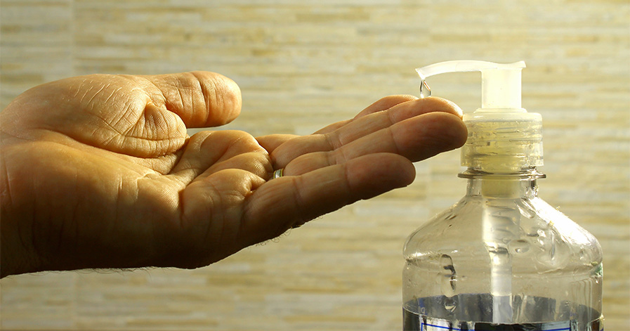Hand taking sanitizer from dispenser