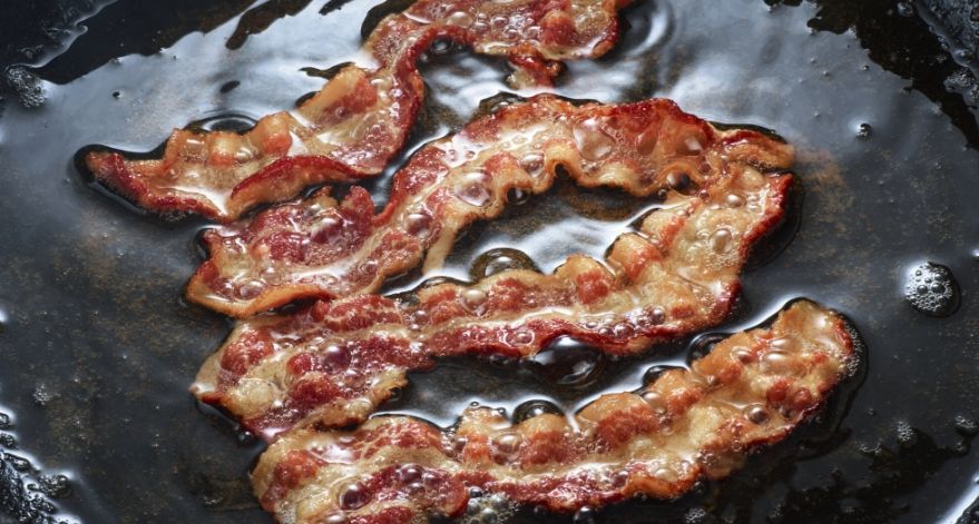 Bacon grilling on a pan.