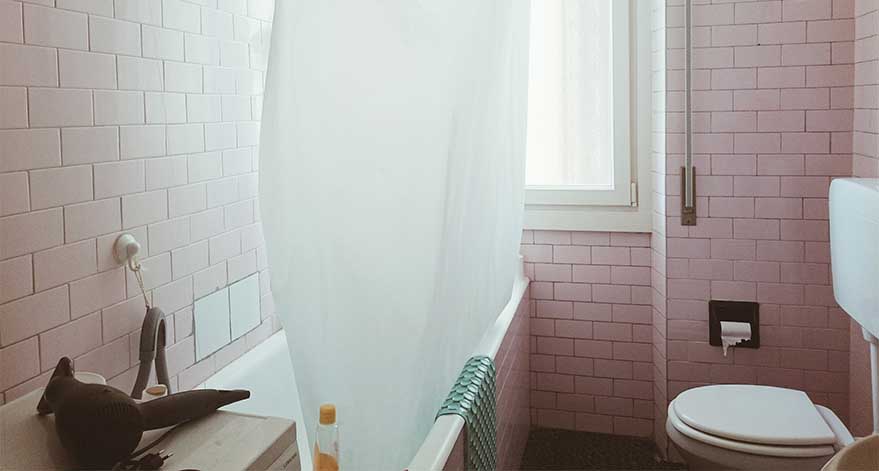 A white shower curtain hanging in a bathroom.