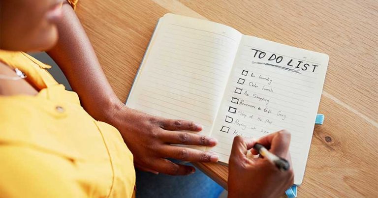 A woman sitting down creating a cleaning checklist.